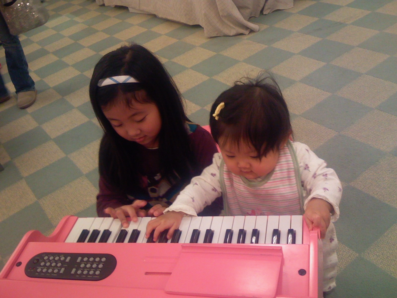 baby picture of Phoebe playing piano with older sister